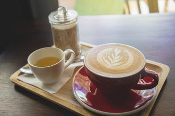 aroma coffee red cup latte art and tasty cake on wood table in coffee shop with vintage dark tone and copy space