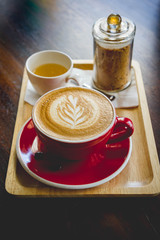 aroma coffee red cup latte art and tasty cake on wood table in coffee shop with vintage dark tone and copy space