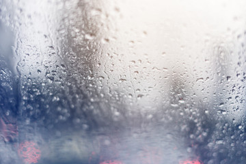 blur image of water car window glass with background of street in raining season