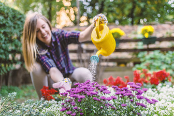 Woman Watering Flower Garden Plants. woman taking care of her plants ( and watering them ) in her garden.