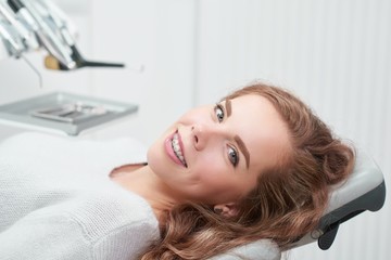 Happy young ginger haired woman with braces smiling to the camera sitting in a dental chair at the clinic waiting for examination copyspace positivity healthcare medicine dentistry people smile.