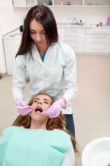 Vertical shot of a professional female dentist working examining teeth of her young patient profession occupation job doctor service medicine healthcare dentistry hygiene concept.