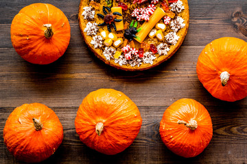 Homemade pie for halloween decorated gummy spiders among pumpkins on wooden background top view