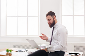 Fototapeta premium Serious businessman with laptop in modern white office