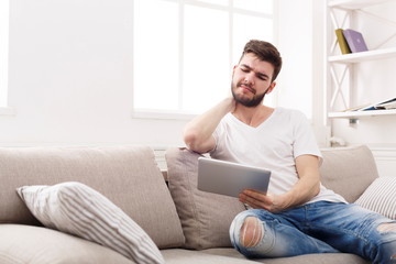Young man at home with tablet feel pain