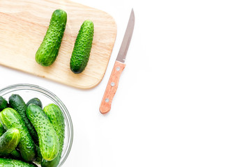 Make salad with fresh cucumbers. Vegetables on cutting board near knife on white background top view copyspace