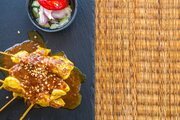 Chicken satay on black dish made from stone on sack fabric table