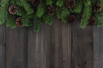 Christmas fir tree branches and pine on dark rustic wooden background with copy space for text