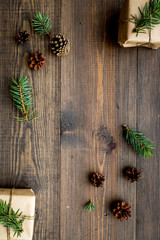 Gifts for new year wrapped in craft paper near spruce branches and cones on wooden background top view pattern copyspace