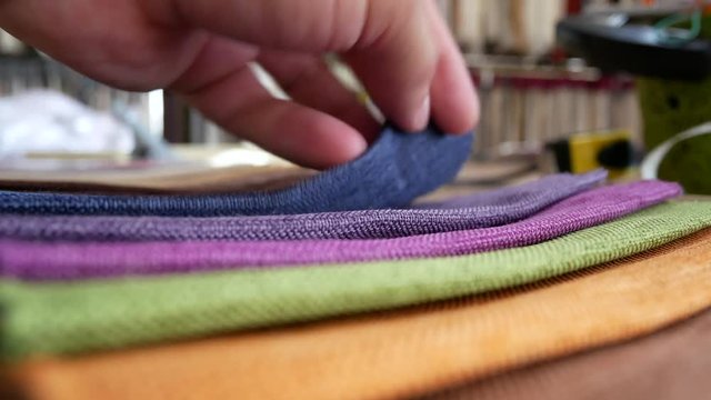 Fashion designer working on table. Taylor looks cotton fabric. Clothing design. Pattern construction. Tailor tools and fabrics. Hand of male tailor touching fabric texture in workshop studio