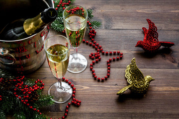 Champagne for celebrate new year. Glasses, bottle in bucket, spruce branch, decoration on wooden background