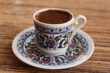 Traditional black coffee in a cup on small plate with colorful design