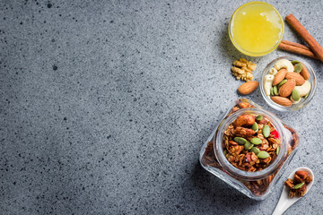 Maple honey cinnamon granola in a glass jar on concrete background. Top view, space for text.