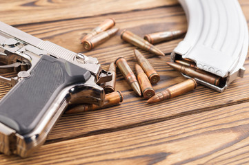Single metal glossy pistol and silver magazine with scattered bullets for assault rifle on old...