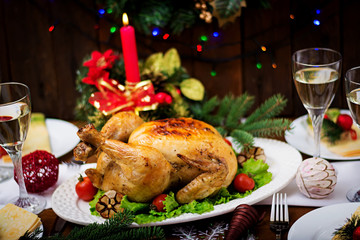 Baked turkey or chicken. The Christmas table is served with a turkey, decorated with bright tinsel and candles. Fried chicken, table. Christmas dinner.