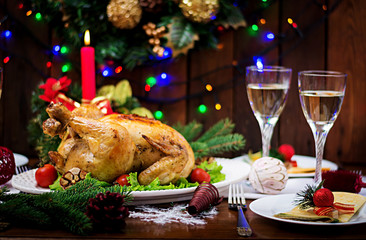 Baked turkey or chicken. The Christmas table is served with a turkey, decorated with bright tinsel and candles. Fried chicken, table. Christmas dinner.