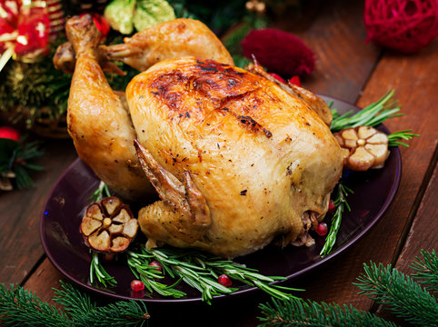 Baked turkey or chicken. The Christmas table is served with a turkey, decorated with bright tinsel and candles. Fried chicken, table. Christmas dinner.