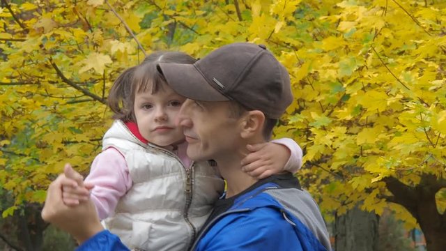 A man is playing with a child in an autumn park. Father and daughter are dancing in nature.
