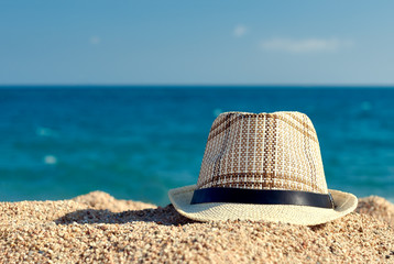 Men’s sunhat on the beach sand against sea.