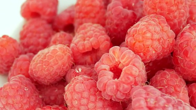 Group of Ripe Juicy Red Raspberries Rotates on the White Background