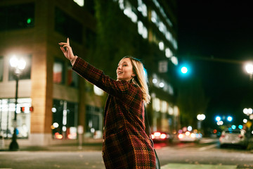 young blond woman hailing a taxi