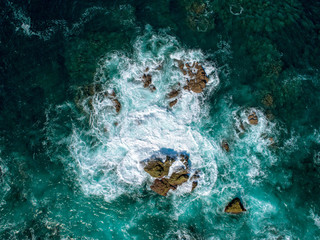 Aerial View of Waves Breaking on Rock