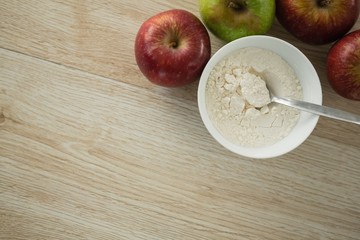 Directly above shot of flour in bowl by apples