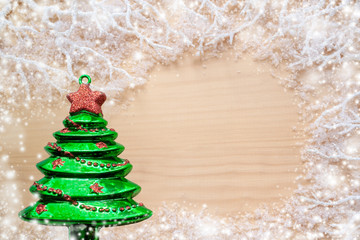 White frosty branches, covered with snow, green glass toy Christmas tree and copy space on natural wooden background.