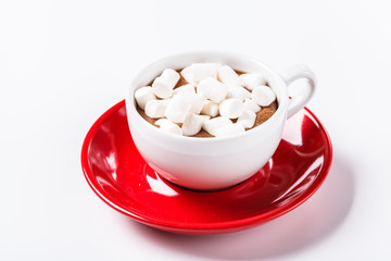 Hot chocolate and marshmelow in a white cup on a red plate on a knitted warm blanket. Christmas, horizontal