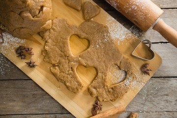 Pastry dough and pastry cutter on cutting board by rolling pin