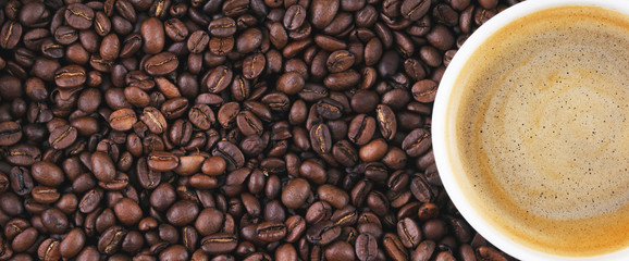 Fried coffee beans. Coffee mug on the background of coffee beans. Panorama, banner.