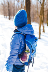 Boy with backpack in woods in winter.