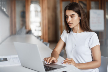 Young woman using a notebook computer watching streaming movies or listening to online music in university campus.