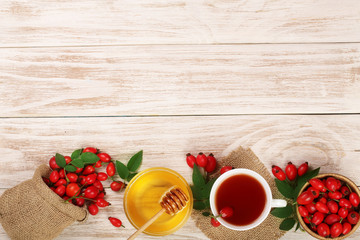 tea with rose hips and honey on white wooden background with copy space for your text. Top view
