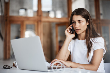 Portrait of serious young woman talking to a customer on phone running her successful online business making cat videos.