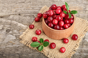 Cranberry with leaf in bowl on old wooden background