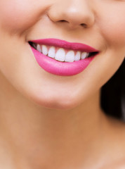 Fototapeta premium Woman smile. Teeth whitening. Dental care. Beautiful girl with clean skin of the face and pink lipstick. Close-up