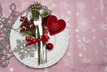 Christmas table place setting with pine branches,ribbon and bow.