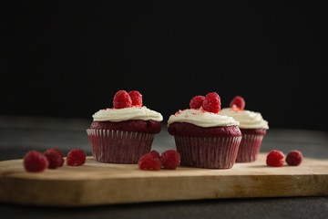 Cupcakes on cutting board against black background