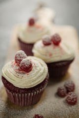Close up of cupcakes with raspberries on cutting board
