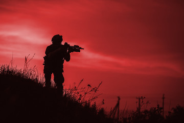 Fototapeta na wymiar Silhouette of military soldier or officer with weapons at night. shot, holding gun