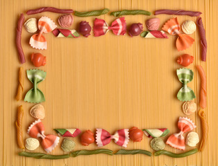 Frame from macaroni. Texture from colored macaroni. Italian cuisine. National food of Italy. Assortment of pasta. Food program. Produce with flour.
