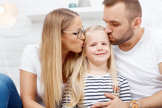Happy family at home in love kissing child