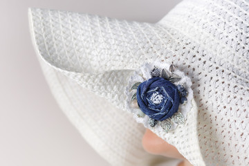 Portrait of a mysterious woman in a white hat with a brooch made of denim handmade. Side view