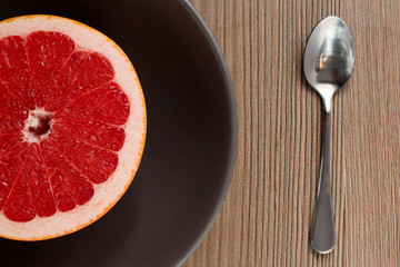 Grapefruit cut in a half in a plate and a spoon
