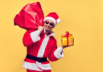 Santa Claus. Young Happy Santa Man. Christmas Santa sack bag Presents gifts. Portrait Handsome Fashion guy Having Fun Smiling. New Year. Emotional Confident Santa Claus. Stylish Colorful Xmas Holiday