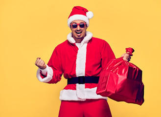 Fototapeta na wymiar Santa Claus. Young Happy Santa Man Winner Gesture. Handsome Fashion guy, Christmas Santa sack bag, Presents Having Fun. New Year. Emotional Sporty Confident Santa Claus. Stylish Colorful Xmas Holiday