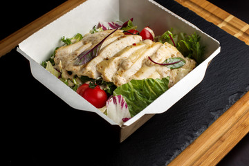 Salad with chicken on a paper box