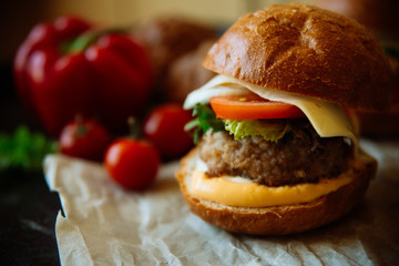 Big sandwich - hamburger with juicy chicken burger, cheese, tomato, and red onion on black background