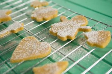 High angle view of powdered sugar on cookies over cooling rack